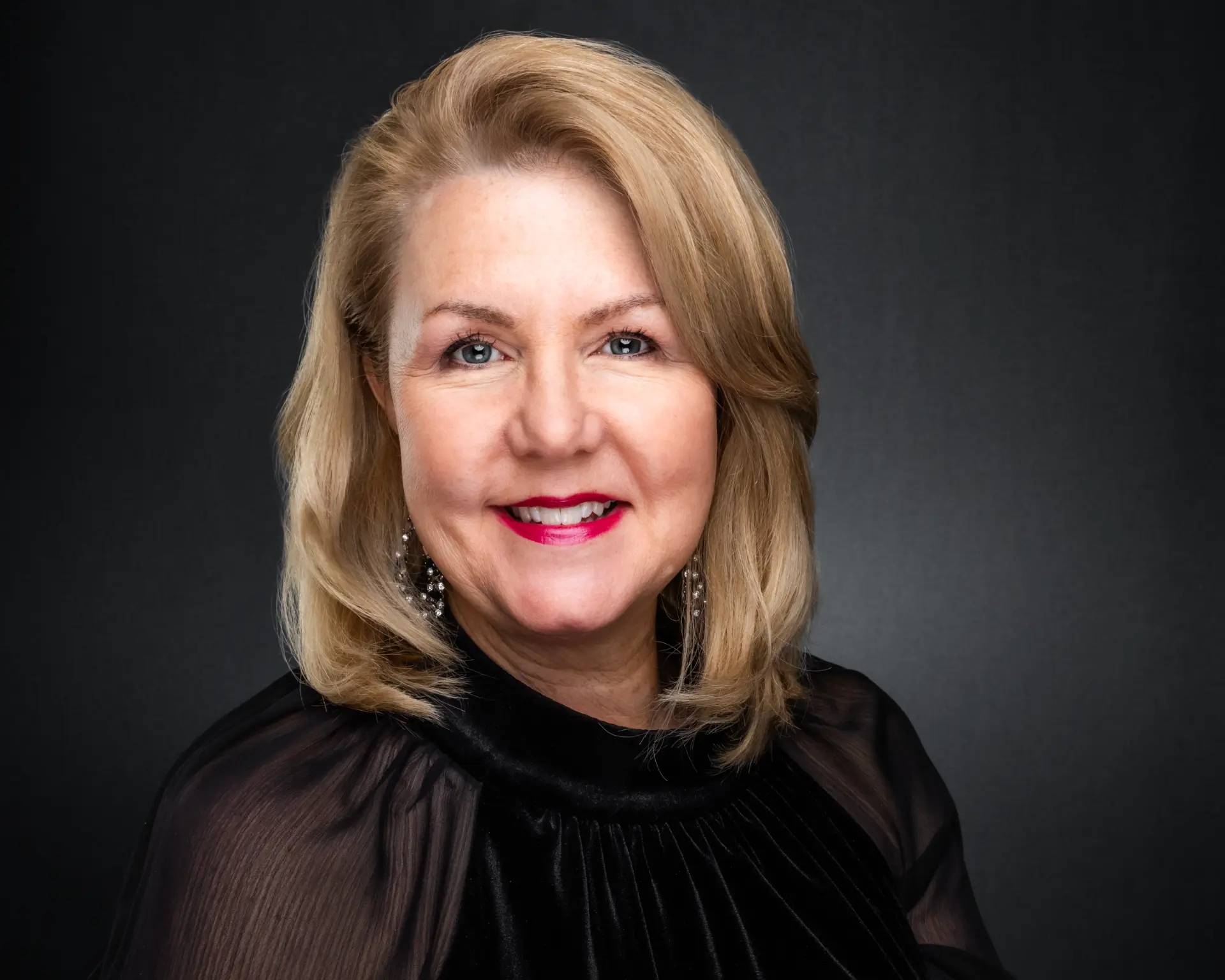 Studio headshot of a professional woman in black with soft blonde hair